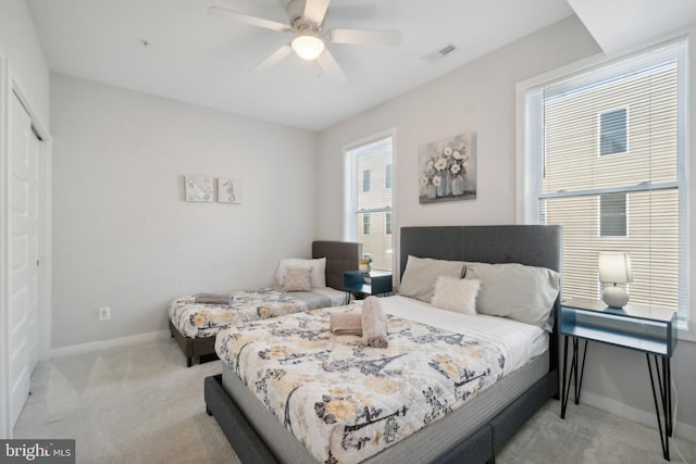bedroom with a closet, visible vents, light carpet, baseboards, and a ceiling fan