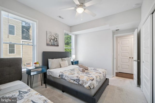 bedroom featuring baseboards, ceiling fan, light colored carpet, and visible vents