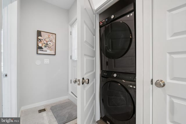 laundry area with laundry area, stacked washing maching and dryer, baseboards, and tile patterned floors