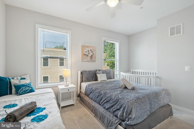 bedroom with light colored carpet, baseboards, visible vents, and a ceiling fan