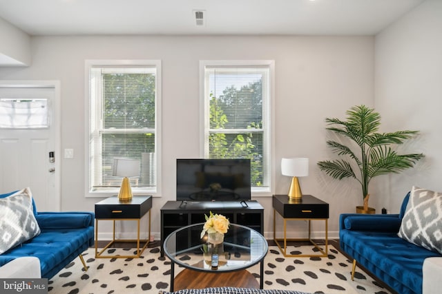 living area with baseboards and visible vents