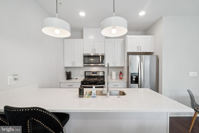 kitchen with stainless steel appliances, white cabinetry, and decorative light fixtures