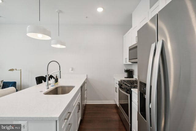 kitchen with white cabinets, appliances with stainless steel finishes, a sink, a peninsula, and baseboards