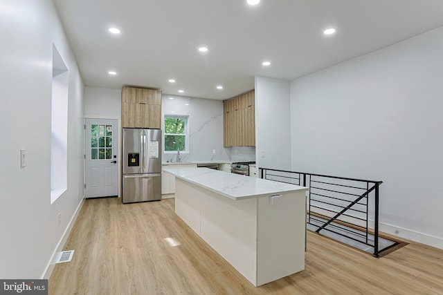 kitchen with stainless steel appliances, modern cabinets, light wood finished floors, and a center island
