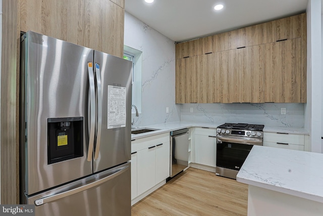 kitchen featuring a sink, modern cabinets, light stone countertops, and stainless steel appliances