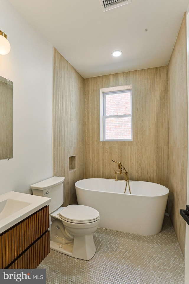 full bathroom with a freestanding bath, vanity, toilet, tile patterned floors, and visible vents
