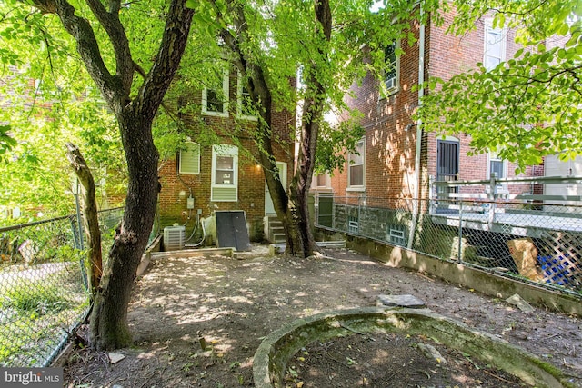 rear view of property featuring brick siding, central air condition unit, and fence