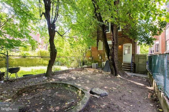view of yard featuring central AC, a fenced backyard, and entry steps