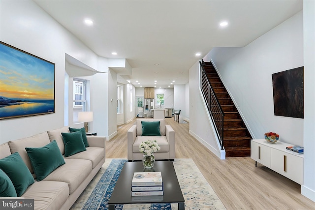 living room featuring stairs, recessed lighting, baseboards, and light wood-style floors