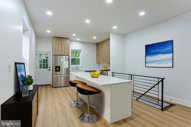 kitchen with a center island, appliances with stainless steel finishes, modern cabinets, and light wood-style floors