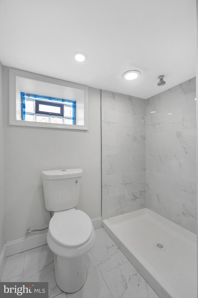bathroom featuring toilet, baseboards, a marble finish shower, and marble finish floor