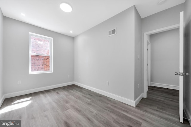 spare room featuring visible vents, baseboards, and wood finished floors