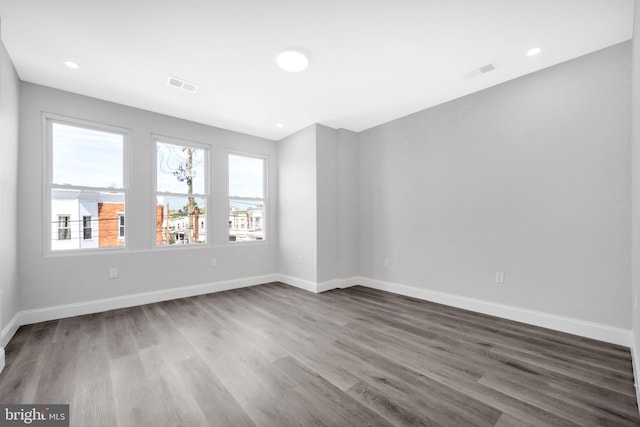empty room with baseboards, visible vents, and dark wood finished floors
