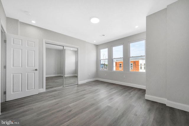 unfurnished bedroom with baseboards, recessed lighting, dark wood finished floors, and a closet