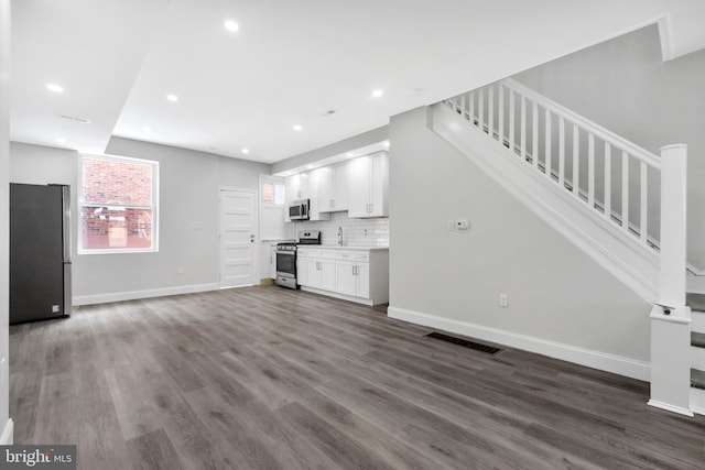 unfurnished living room with dark wood finished floors, recessed lighting, baseboards, visible vents, and stairway