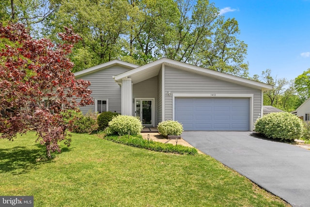 mid-century home featuring an attached garage, driveway, and a front lawn