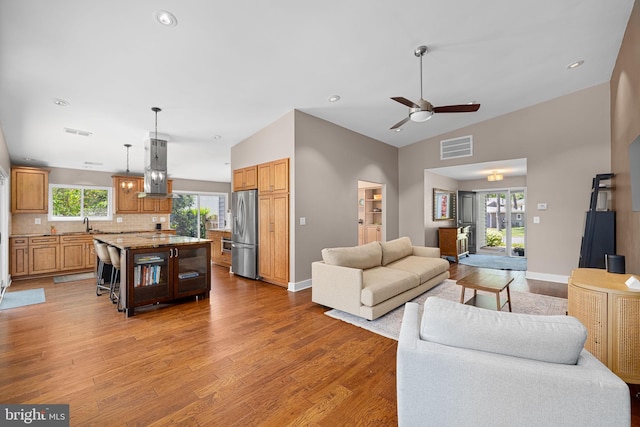 living area with ceiling fan, visible vents, baseboards, and light wood-style floors