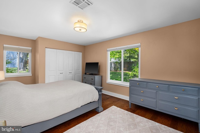 bedroom featuring a closet, baseboards, dark wood-type flooring, and visible vents