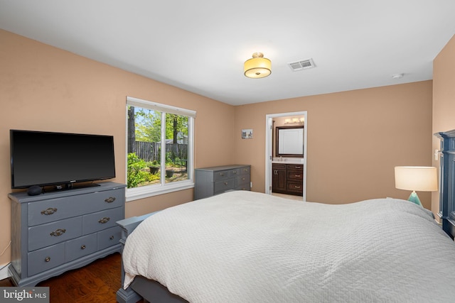 bedroom featuring dark wood-style flooring, baseboards, visible vents, and ensuite bathroom