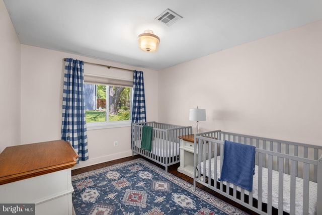 bedroom with visible vents, baseboards, and wood finished floors