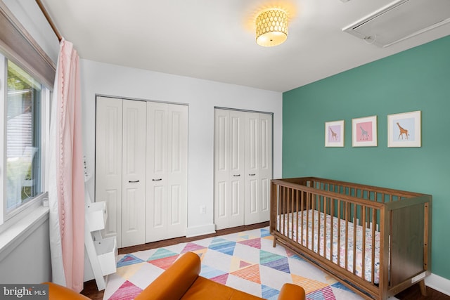 bedroom with baseboards, multiple closets, and attic access