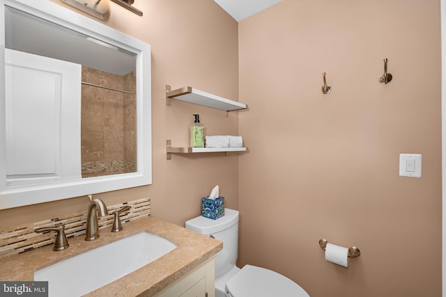 full bathroom with vanity, toilet, and tiled shower