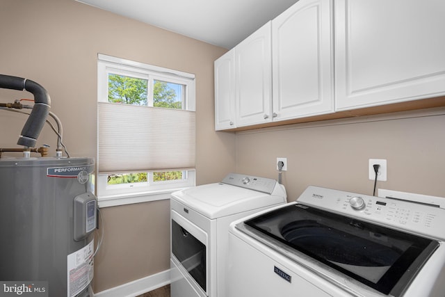 laundry area with baseboards, washing machine and dryer, cabinet space, and electric water heater