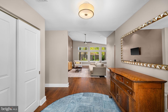 hall featuring baseboards, visible vents, wood finished floors, and lofted ceiling