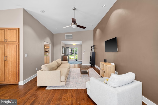 living area featuring visible vents, baseboards, a ceiling fan, dark wood finished floors, and vaulted ceiling