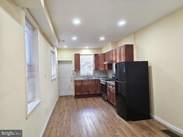 kitchen with stainless steel range with gas cooktop, freestanding refrigerator, a sink, and baseboards