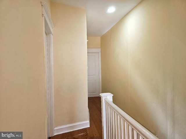 corridor with baseboards, wood finished floors, and an upstairs landing