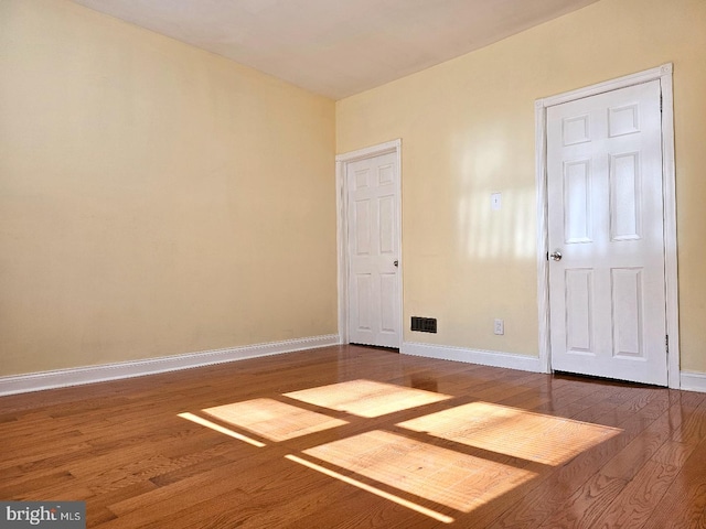 unfurnished bedroom with baseboards, wood finished floors, and visible vents