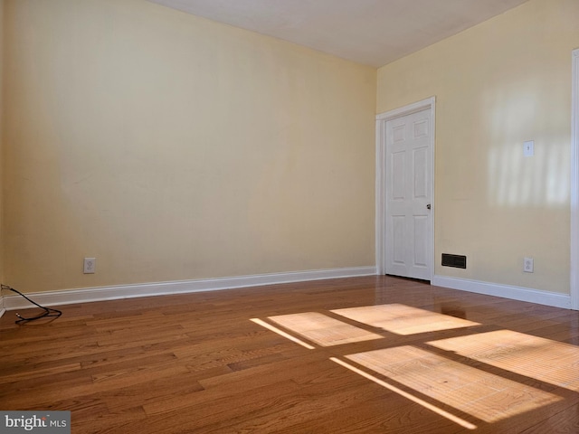 spare room featuring baseboards and wood finished floors