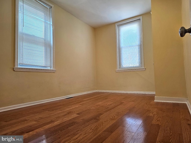 empty room featuring baseboards, dark wood-style flooring, and vaulted ceiling