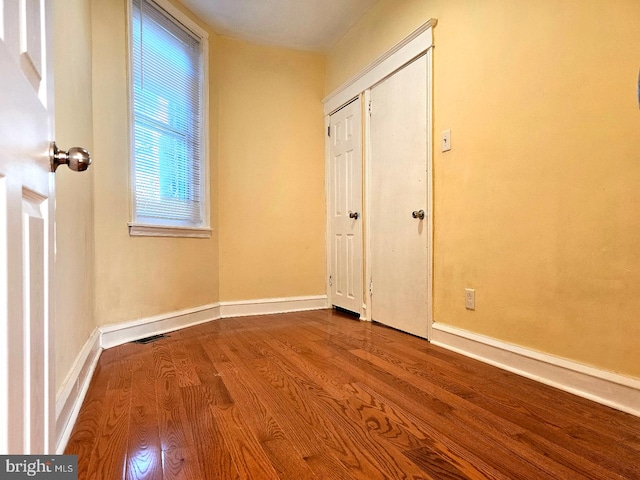 unfurnished room with baseboards, wood finished floors, and visible vents