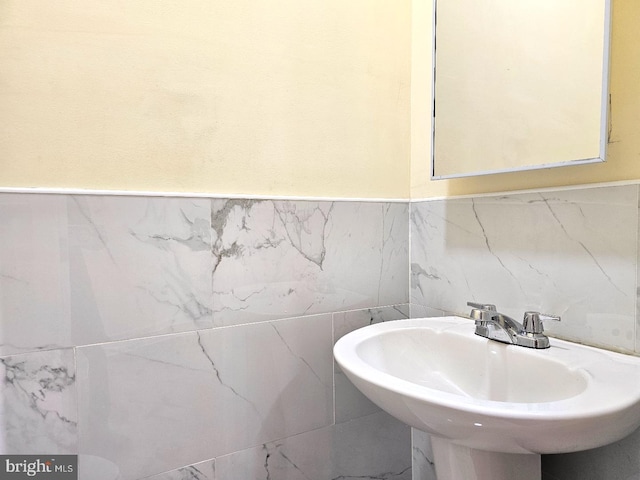 bathroom featuring a sink, a wainscoted wall, and tile walls