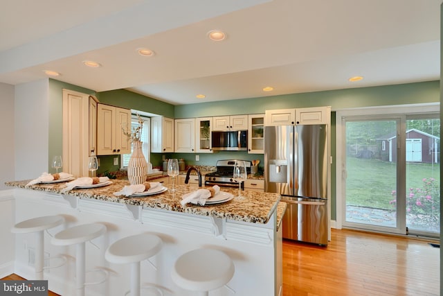 4255 Darleigh Rd, Baltimore, MD 21236 - kitchen with stainless steel appliances, a kitchen breakfast bar, light stone counters, light wood-style floors, and a peninsula