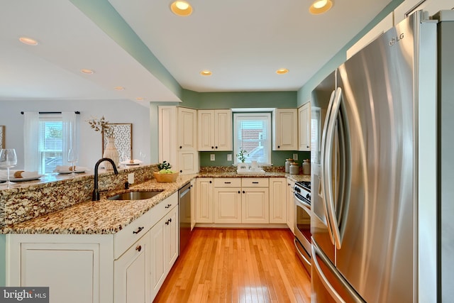 4255 Darleigh Rd, Baltimore, MD 21236 - kitchen with stainless steel appliances, a sink, a peninsula, light stone counters, and light wood-type flooring