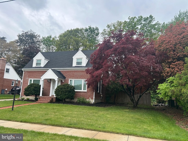 new england style home featuring brick siding and a front lawn
