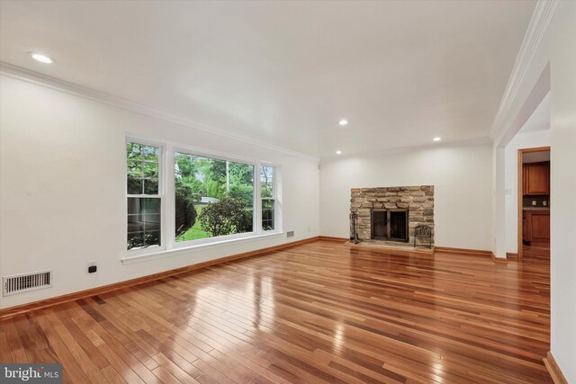unfurnished living room featuring ornamental molding, light wood finished floors, a fireplace, baseboards, and recessed lighting