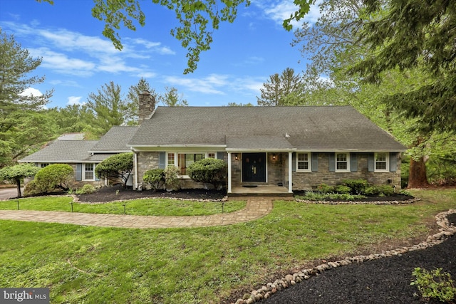 view of front facade featuring stone siding, a chimney, a front yard, and a shingled roof