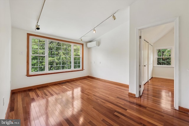 empty room featuring track lighting, a wall mounted air conditioner, and baseboards