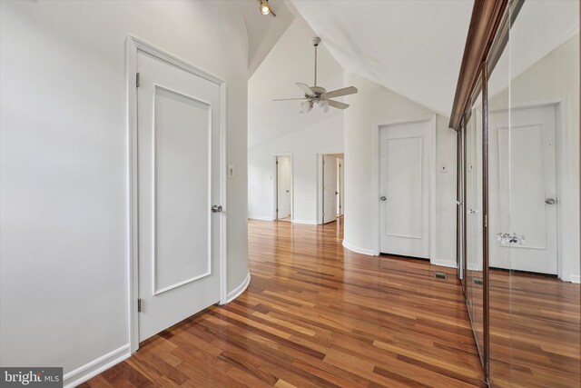 empty room featuring a ceiling fan, wood finished floors, baseboards, and high vaulted ceiling