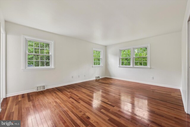 spare room featuring wood-type flooring and baseboards