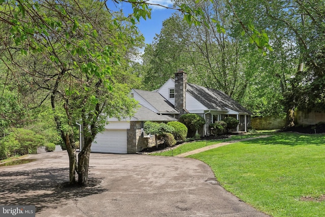 view of front of home with asphalt driveway, a chimney, and an attached garage