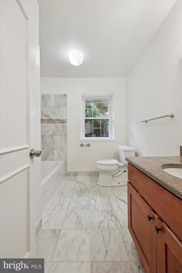 full bathroom with marble finish floors, toilet, vanity, a tub to relax in, and baseboards