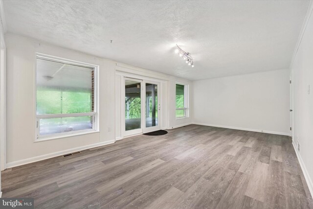 spare room featuring a textured ceiling, wood finished floors, and baseboards