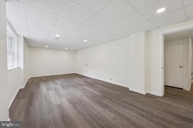 below grade area featuring dark wood-style floors, a drop ceiling, baseboards, and recessed lighting