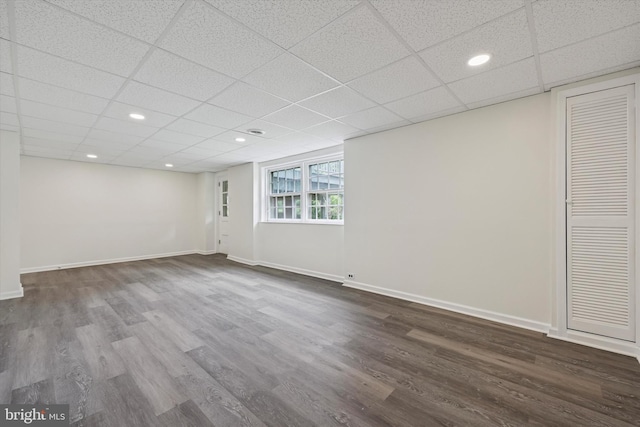 below grade area with dark wood-style floors, a paneled ceiling, baseboards, and recessed lighting