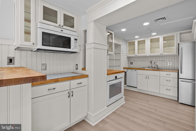 kitchen with white appliances, wooden counters, white cabinetry, visible vents, and glass insert cabinets